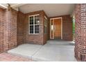 Inviting front porch featuring a solid wood door, brick columns and walls, and concrete walkway at 6533 S Ouray St, Aurora, CO 80016