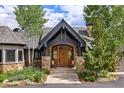 Inviting front entrance featuring a grand wooden door with stone accents, surrounded by lush landscaping at 174 Sage Dr, Breckenridge, CO 80424