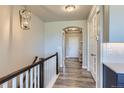 Bright hallway with wood floors, staircase with white rails, arched doorway, and modern light fixture at 6805 Zebra Grass Ln, Parker, CO 80138