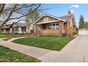 Beautiful brick home featuring a covered porch, manicured lawn, and classic architectural details at 916 Adams St, Denver, CO 80206