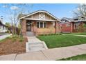 Charming brick home featuring a covered front porch, well-maintained lawn, and beautiful architectural details at 916 Adams St, Denver, CO 80206