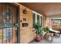 Inviting covered porch with a decorative door, brick facade, and cozy seating area at 916 Adams St, Denver, CO 80206