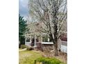 Charming two-story red home with blossoming tree and well-maintained front yard at 8335 Deframe Ct, Arvada, CO 80005