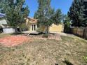 Large backyard with a wooden deck, brick patio, mature trees, and plenty of space for outdoor activities at 5745 S Quatar Ct, Centennial, CO 80015