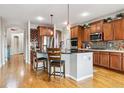 Bright kitchen featuring wood floors, stainless appliances, wood cabinets, and an island at 11545 S Flower Mound Way, Parker, CO 80134