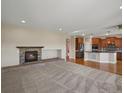 Cozy living room with stone fireplace that opens to an open-plan kitchen at 11545 S Flower Mound Way, Parker, CO 80134