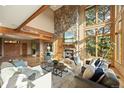Bright living room with a stone fireplace, wooden beams, and large windows overlooking trees at 91 Hess Ave, Golden, CO 80401