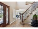 Grand foyer with hardwood floors, decorative front door, and a curved staircase with iron railings at 3970 White Bay Dr, Highlands Ranch, CO 80126