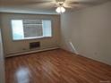 Cozy living room with wood-look floors, a large window, and a classic radiator at 680 S Alton Way # 9A, Denver, CO 80247