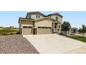 Tan two story home featuring a 3-car garage, stone accents, and well-manicured landscaping at 42830 Ivydel St, Elizabeth, CO 80107