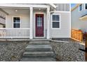 Inviting front entrance with a covered porch and a decorative red door at 2662 E 103Rd Ave, Thornton, CO 80229