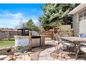 Outdoor kitchen area with built-in grill, countertop, stone accents, table and chairs at 10629 W Glasgow Ave, Littleton, CO 80127