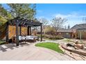 Landscaped backyard with pergola-covered seating area, stone pathway, water feature, and playhouse at 10629 W Glasgow Ave, Littleton, CO 80127