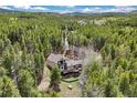 Aerial view of a home with a large deck surrounded by lush forest at 24 Navajo Trl, Evergreen, CO 80439