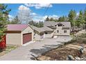 A charming tan home with a three car garage, and red shipping container at 24 Navajo Trl, Evergreen, CO 80439