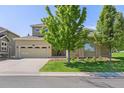 Traditional-style home with a well-maintained lawn, mature tree, and a two-car garage at 6690 S Fenton St, Littleton, CO 80123