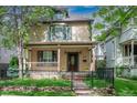 Charming two-story home featuring a covered front porch, black iron fence, and well-maintained lawn at 433 N Ogden St, Denver, CO 80218