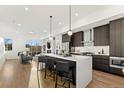 Open-concept kitchen features a large island with seating, stainless steel appliances, and dark wood cabinetry at 2144 Applewood Dr, Lakewood, CO 80215