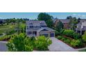 Charming two-story home with a stone facade, a covered porch and manicured landscaping surrounding the driveway at 14620 Prairie Sky Ln, Broomfield, CO 80023