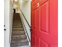 Entryway with a bright red door, ascending carpeted stairs, and a black railing, creating a welcoming atmosphere at 8751 Pearl St # J3, Thornton, CO 80229