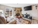 Cozy living room features stone fireplace, plush sofa, mounted TV, and balcony access at 4400 S Quebec St # 107, Denver, CO 80237