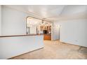 Cozy living room with an archway, neutral carpet, and seamless flow to the kitchen area at 1683 Monroe St, Strasburg, CO 80136