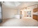 Bright living room featuring a skylight and neutral carpeting with open floor plan at 1683 Monroe St, Strasburg, CO 80136