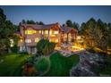 Expansive backyard with lush lawn, a stone fire pit, and beautiful landscaping at 5 Walden Ln, Cherry Hills Village, CO 80121