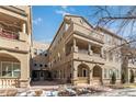 Exterior view of tan building with balconies, arched entryways, and winter landscaping at 40 Madison St # 103, Denver, CO 80206