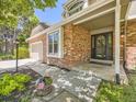 Inviting brick front exterior featuring a covered entrance, lush landscaping, and a convenient two-car garage with a basketball hoop at 7782 S Louthan St, Littleton, CO 80120