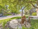 Relaxing front yard featuring Adirondack chairs, a small table, and shade trees, creating a welcoming curb appeal at 7782 S Louthan St, Littleton, CO 80120