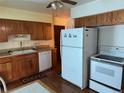 Functional kitchen featuring wood cabinets, white appliances, and a double basin sink with updated hardware at 12046 W Green Mountain Dr, Lakewood, CO 80228