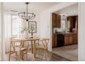 Inviting dining area with a round wooden table, modern chandelier, and adjacent kitchen with wood cabinets at 916 Florence St, Aurora, CO 80010