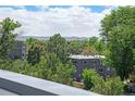 Exterior view of a modern apartment complex, partially obscured by mature trees with a mountain view in the background at 2726 Federal Blvd # 1, Denver, CO 80211