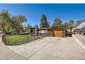 View of the home highlighting the attached garage, brick accents, and well-manicured front yard with black iron fence at 975 S Queen Way, Lakewood, CO 80226