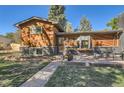 Exterior shot showcasing the beautiful woodwork, brick details, and landscaped front yard with inviting porch seating at 975 S Queen Way, Lakewood, CO 80226