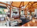Cozy living room featuring exposed wood beams, plush seating, and a seamless flow to dining area at 9250 Steeplechase Dr, Franktown, CO 80116