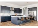 Spacious kitchen with large island, barstool seating, modern backsplash, pendant lights, and stainless steel appliances at 5985 Galena St, Denver, CO 80238