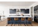 Modern kitchen featuring a large island with bar seating, stylish pendant lighting, and stainless steel appliances at 5985 Galena St, Denver, CO 80238