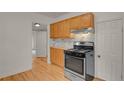 Kitchen features stainless steel gas range, wooden cabinets, and hardwood floors at 127 S Perry St, Denver, CO 80219