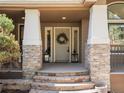 Inviting front porch with stone pillars, decorative lanterns, and wreath-adorned door at 484 Hyland Dr, Castle Rock, CO 80108