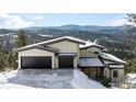 Modern home exterior with two-car garage and mountain backdrop at 26467 Bell Park Dr, Evergreen, CO 80439