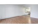 Living room with hardwood floors flowing into a kitchen area with white cabinets and stainless steel appliances at 755 S Alton Way # 9D, Denver, CO 80247