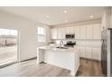 Modern kitchen boasts stainless steel appliances, white cabinetry, an island, and a stylish breakfast bar at 11052 Snowdon St, Parker, CO 80134