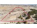 This aerial view showcases the expansive acreage featuring a home, outbuildings, and riding arena with a striking red perimeter at 1991 County Road 132, Elizabeth, CO 80107