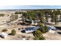 Aerial view of the residence with solar panels and outbuildings, surrounded by trees and vast open land at 1991 County Road 132, Elizabeth, CO 80107