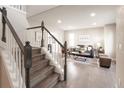 Sunlit living room features hardwood floors and staircase with charming modern decor at 1772 Eisenhower, Louisville, CO 80027