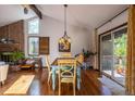 Dining room with hardwood floors, brick fireplace, vaulted ceiling, and sliding door access to the deck at 1424 Cypress Cir, Lafayette, CO 80026