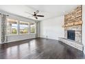Bright living room featuring a stone fireplace, dark wood floors, and lots of natural light at 13440 Monaco St, Thornton, CO 80602