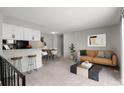 Open-concept living room with modern furniture, plush carpet, and a bar leading to the dining area at 1289 S Wheeling Way, Aurora, CO 80012